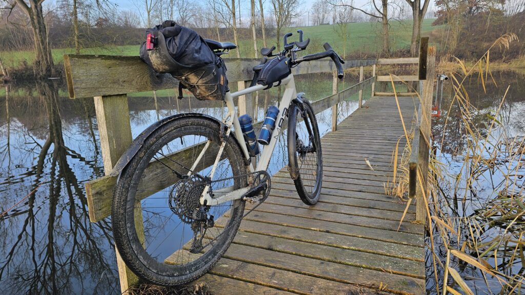 Bepacktes Gravelbike auf einem Holzsteg über einem Teich