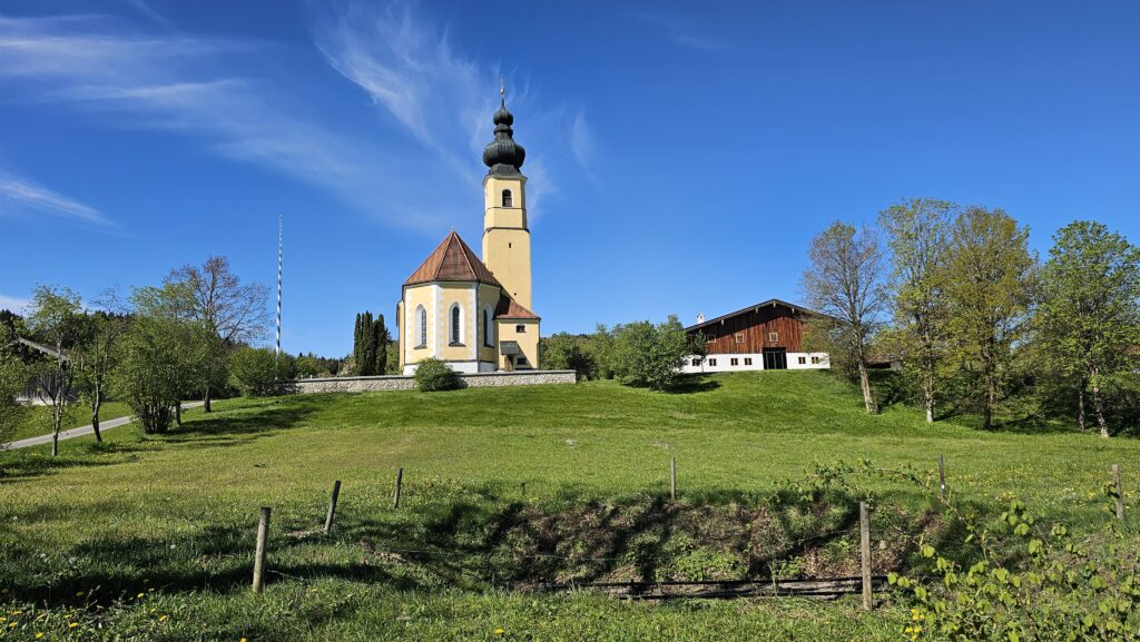 Barocke Dorfkirche mit Zwiebelturm hinter einer Wiese