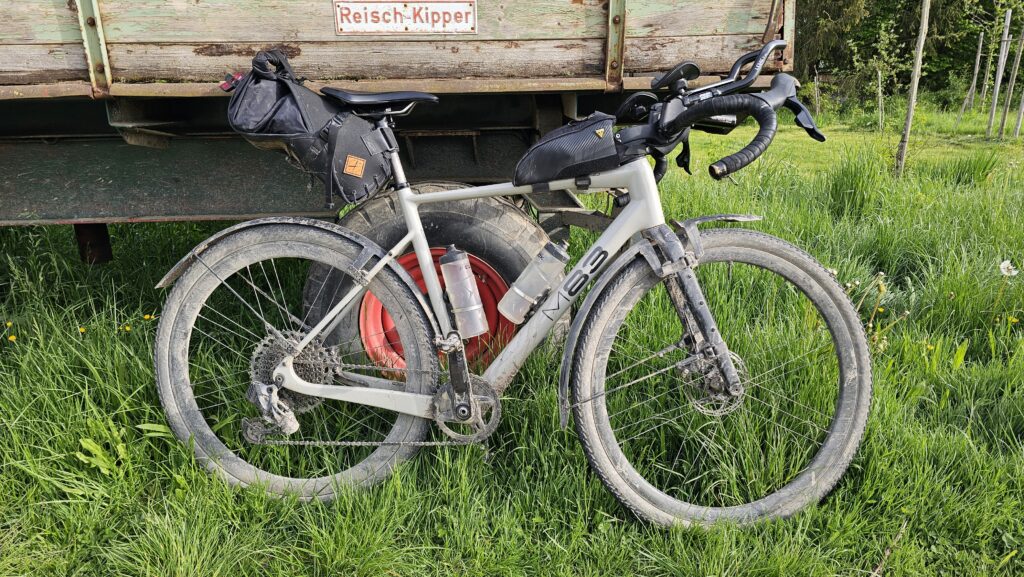 Schlammiges Gravelbike an einem Anhänger in der Wiese