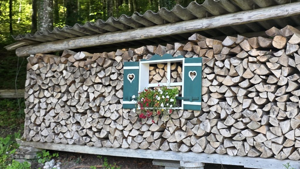Holzstapel mit Fenster und Blumenkästen bei Weißenbach